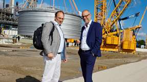 Raffinerie-Chef Lars Bergmann (rechts) hat sich mit DVZ-Autor Kai Eckert getroffen. Im Hintergrund wird der neue Tankbehälter auf dem Fundamentsockel abgesetzt.