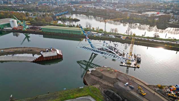Die Stabbogenbrücke wurde mit Hilfe von zwei schwimmenden Schwerlastkränen  eingehoben. Der „Matador“ und der „Hebo-Lift 8“ wurden aus Rotterdam geholt: Der eine kann bis zu 400 Tonnen tragen, der andere 300 Tonnen.