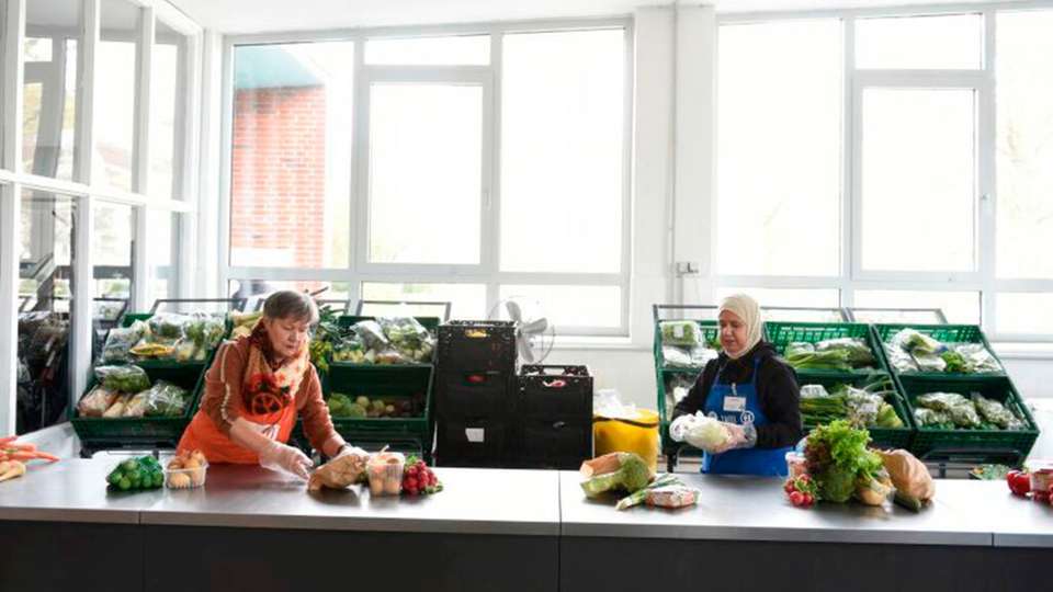 Zwei Mitarbeiterinnen sortieren Lebensmittelspenden bei der Tafel in Lübeck.