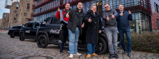 Daumen hoch für die Elektromobilität: Das Fuhrpark-Team von Coca-Cola feiert die vollständige Elektrifizierung der firmeneigenen Pkw- und Transporter-Flotte mit insgesamt 1.600 Fahrzeugen. 